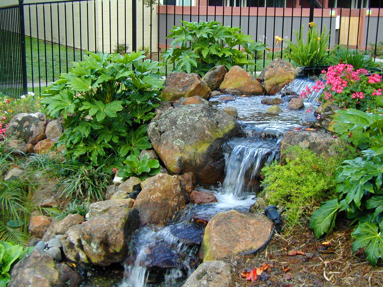 Một dòng suối nhân tạo sẽ trở nên sống động hơn khi được kết hợp với các yếu tố trang trí khác. Một vài bụi trúc nhỏ, những khóm cỏ lá gừng, hoa lan đá hoặc sen cạn điểm xuyết khiến toàn bộ khung cảnh trở nên mềm mại